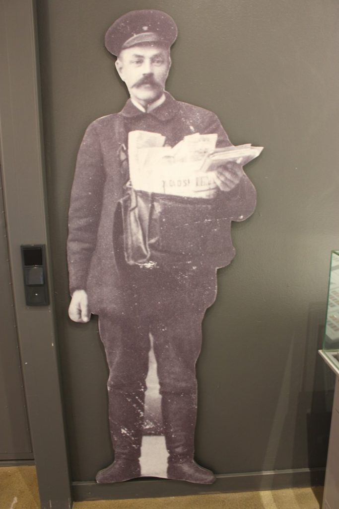 Pahvinen postimiehen kuva kiinnitettynä seinään.
